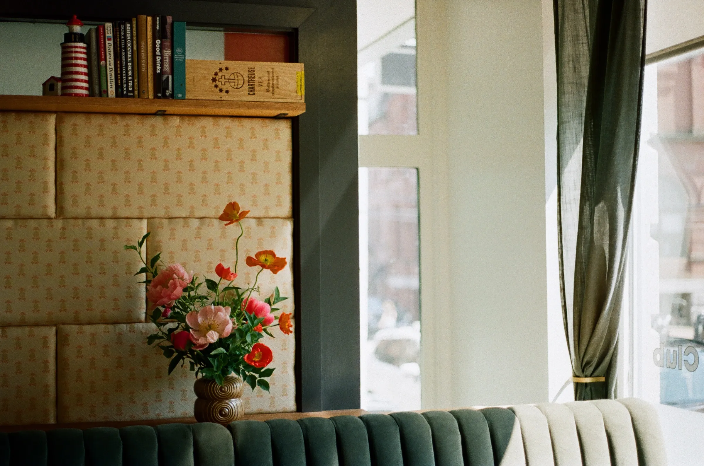 Poppies arranged in a vintage vase beside a cafe window, warm afternoon light
